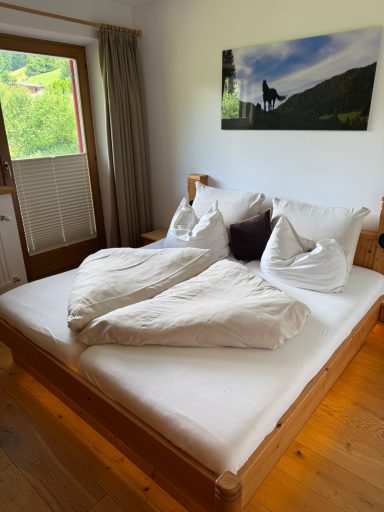 Ein Schlafzimmer mit einem Bett, weißen Kissen und Decken sowie grüner Aussicht.